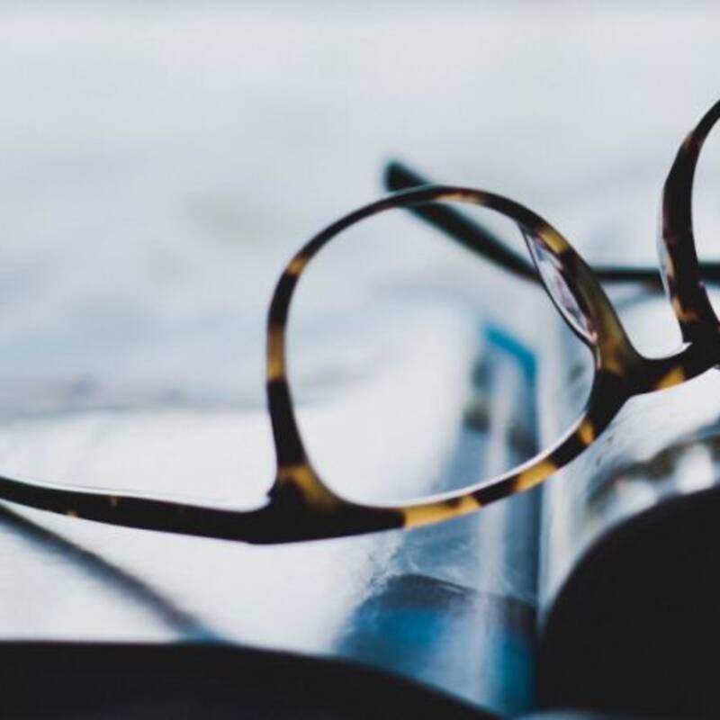 Abgelegte Brille auf offenem Buch