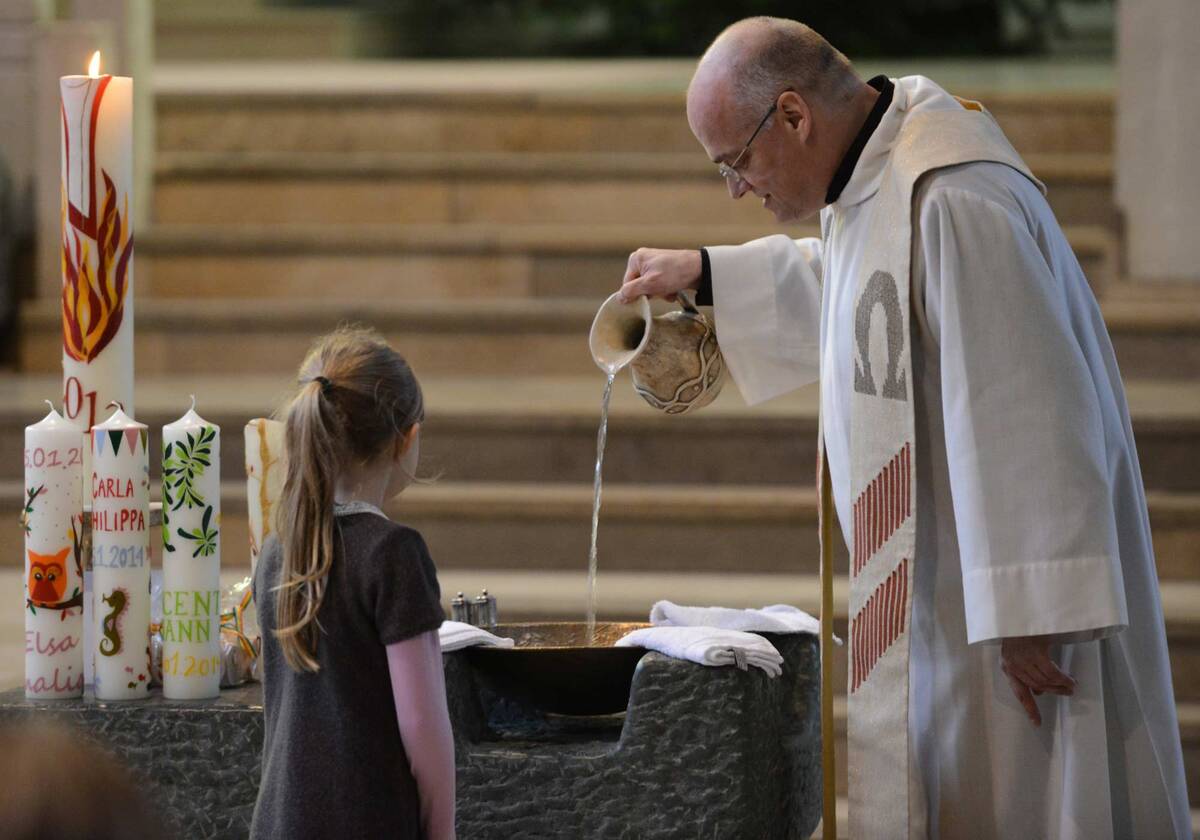 Priester mit Taufwasser Priester bereitet das Taufbecken für bevorstehende Taufe vor