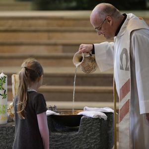 Priester bereitet das Taufbecken für bevorstehende Taufe vor